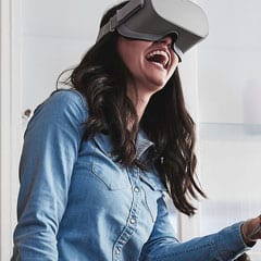 Brunette in denim blouse wearing grey oculus go and smiling